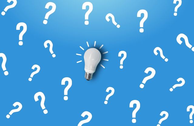 白い電球の周りにたくさんの白いハテナマーク